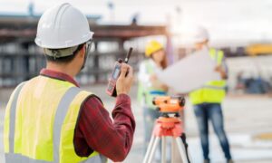 Construction worker using a radio on site, overseeing project planning and collaboration with team members,
